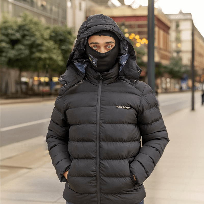 Man wearing black luxury detachable hoody puffer jacket AIIB, standing on a city street.